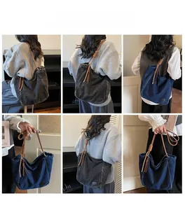 Detail of large denim tote bag showing the textured brown braided rope strap and tassels