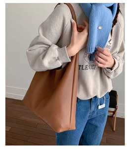 Brown litchi texture tote bag shown on shoulder in a minimalist indoor setting