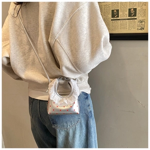 Detailed back view of a silver mini crossbody bag with red polka dots and lace handle decor