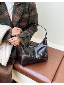 Détail du sac hobo en cuir PU brillant marron foncé avec boucle argentée sur blazer à carreaux