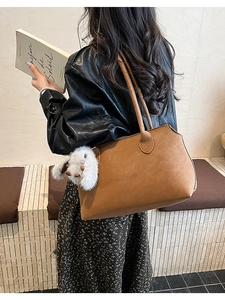 Détail d'un sac cabas en cuir marron avec un charm lapin en peluche blanc en intérieur