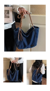 Detail of blue denim tote bag featuring brown rope handles and decorative tassel knot