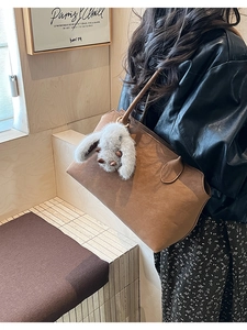 Sac fourre-tout en daim marron avec breloque lapin en peluche dans un décor épuré