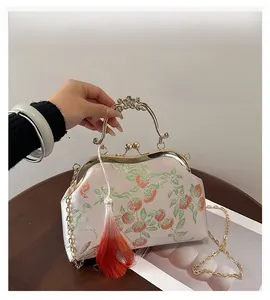 Close-up of pink silk evening bag with persimmon embroidery, gold handle and silk tassel