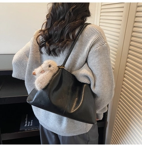 Grand sac cabas en cuir noir avec breloque lapin en peluche sur un pull gris en maille