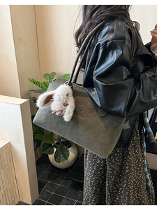 Détail du grand sac cabas en daim vert olive avec un porte-clé lapin en peluche blanc