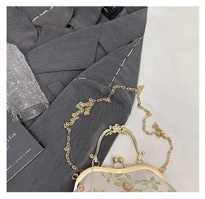 Close-up of exquisite floral embroidery and golden metal frame on this vintage chain bag