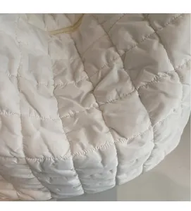 Close-up of white quilted bubble fabric texture showing soft padded square pattern details