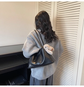 Détail d'un sac cabas en cuir souple noir avec pendentif lapin en peluche sur un modèle