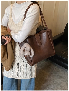 Detail of vintage brown tote bag with smooth PU leather finish and cute bunny charm