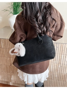 Détail du grand sac cabas noir avec breloque lapin en peluche sur un modèle féminin