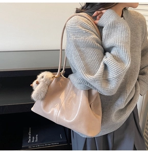 Détail d'un sac cabas en cuir beige avec texture souple et charmant porte-clé peluche