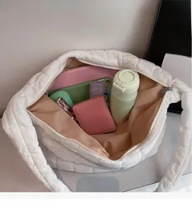 Spacious interior of white quilted tote bag showing tablet, umbrella and water bottle