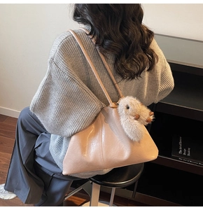 Détail d'un sac cabas en cuir souple avec de longues anses et un charm lapin en peluche