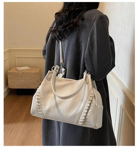 Detail of off-white tote bag with lychee texture and woven rope stitching on shoulder