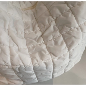 Close-up of white quilted bubble fabric with soft texture and neat stitching details