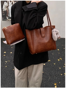 Detail of vintage brown leather tote bag set with a small matching pouch and plush charm