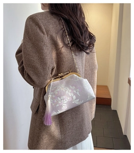 Detail of lavender silk embroidery bag with floral patterns, metal kiss-lock and tassel