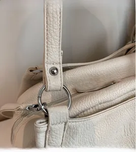Detail of cream white lychee grain leather underarm bag with silver round hardware