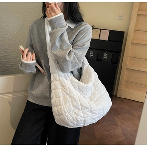 Detail of a large white quilted puffy shoulder bag with soft padded texture and stitching