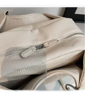 Close-up of smooth dual metal zippers on creamy white lychee textured leather bag