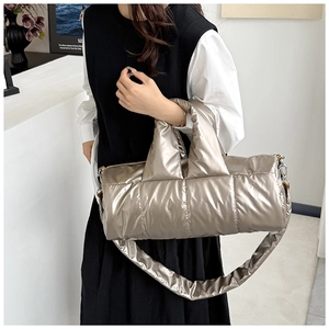 Detail of metallic champagne quilted cylinder bag with puffer texture and shoulder strap