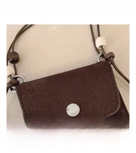 Detail of brown suede mini bag featuring wooden beads and a round silver metal snap button