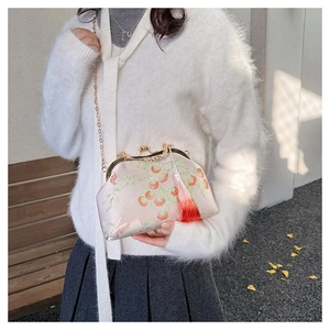 Detail of pink embroidered handbag with strawberry motifs, metal clasp, and orange tassel