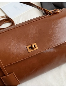 Detailed macro shot of vintage brown leather bag featuring a retro bronze metal twist lock