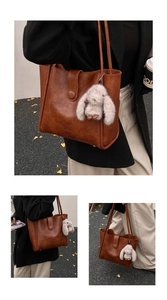 Detailed view of brown leather tote bag with a vintage buckle and plush rabbit charm