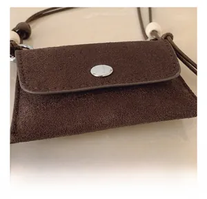 Detail shot of brown suede mini purse with silk strap and metallic snap button