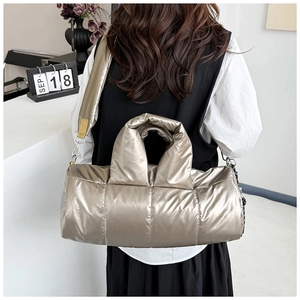 Detail of champagne gold quilted puffer bag with metallic finish and wide shoulder strap