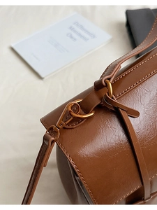 Detail of golden metal buckles and fine stitching on brown vintage Kelly bag