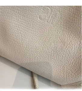 Macro detail of creamy white lychee grain leather handbag with embossed ao logo