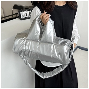 Quilted silver padded cylinder bag shown as a crossbody on a fashion model in a studio