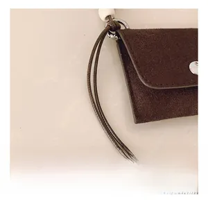 Detail of vintage brown suede mini bag with decorative beaded lanyard and silver snap button