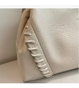 Close-up of off-white leather tote bag with whipstitch hand-woven edge detailing
