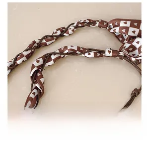 Detail of woven brown and white checkerboard shoulder strap with heart patterns