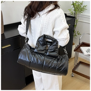 Detail of black quilted puffer boston bag with detachable shoulder strap and silver hardware