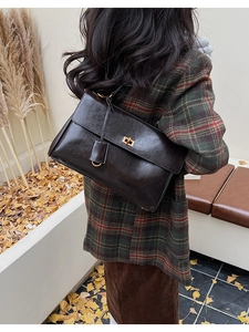 Detail of vintage dark brown faux leather bag with golden turn-lock on a shoulder strap
