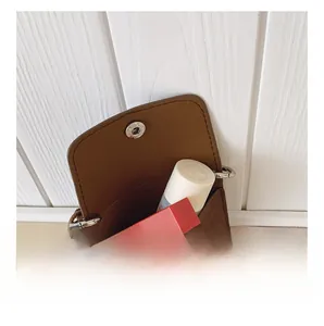 Detailed view of the brown mini crossbody bag interior showing storage space for lipstick