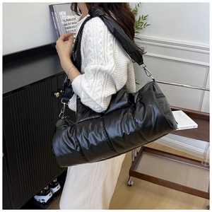 Detail of the black quilted puffer shoulder bag with a wide padded strap and soft texture
