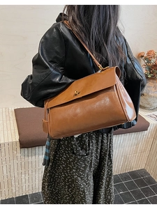 Close-up of a brown retro crossbody bag with a gold metal twist lock and leather texture