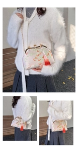 Close-up of pink silk embroidered handbag with golden chain and red silk tassel detail