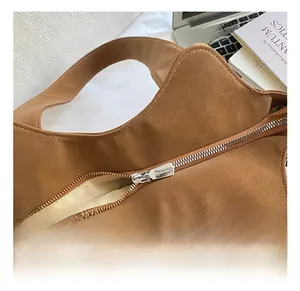 Detail of silver metal zipper and smooth interior lining on a brown tote bag