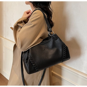 Detail of lychee textured leather tote with woven stitching and embossed logo on model