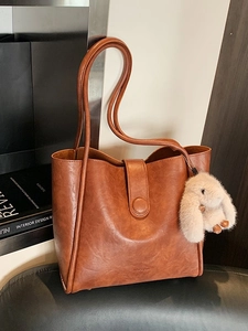 Vintage brown leather tote bag with plush bunny charm for minimalist daily commute