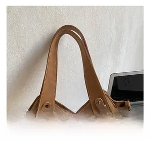 Detail of tan faux leather tote bag showing reinforced handles and silver metal hardware