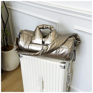 Macro detail of champagne metallic puffer bag with quilted texture on a suitcase