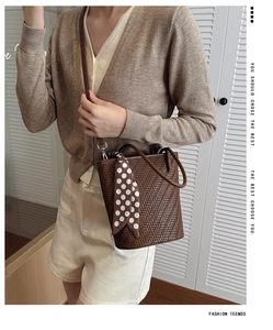 Detail of a brown woven bucket bag featuring a polka dot silk scarf and adjustable strap